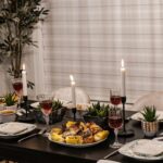 A stylish dining table set for a cozy dinner party with wine and candles.