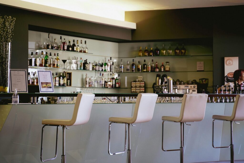 Contemporary bar setting featuring a stylish counter and bar stools with a well-stocked liquor display.
