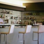 Contemporary bar setting featuring a stylish counter and bar stools with a well-stocked liquor display.