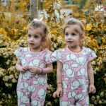Charming twin girls in elephant print dresses amidst autumn blooms in Istanbul.