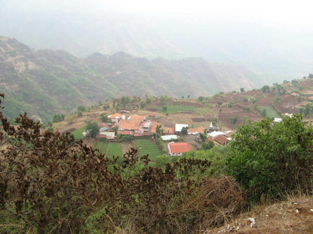 Aerial view of a countryside village surrounded by lush fields and hills.