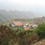 Aerial view of a countryside village surrounded by lush fields and hills.
