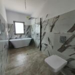 Bright contemporary bathroom with marble tiling, freestanding tub, and natural light in Iași, Romania.