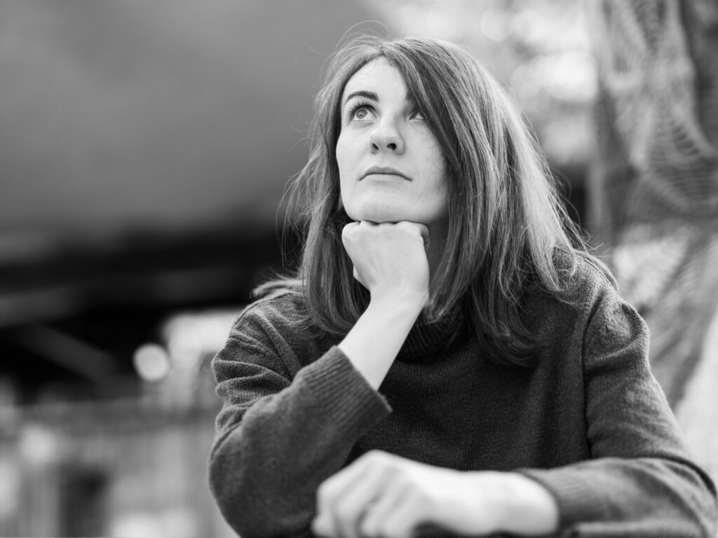 Black and white portrait of a woman gazing thoughtfully outdoors. Emotional and serene.
