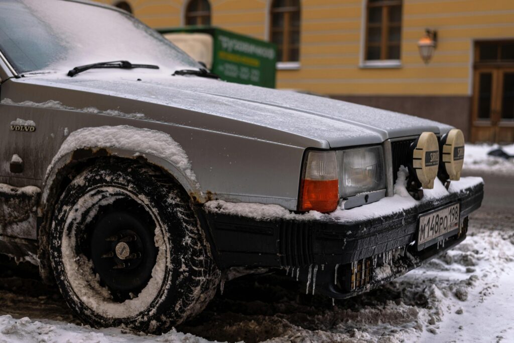 Close-up of a vintage Volvo with snow and ice on city street in winter.