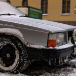 Close-up of a vintage Volvo with snow and ice on city street in winter.
