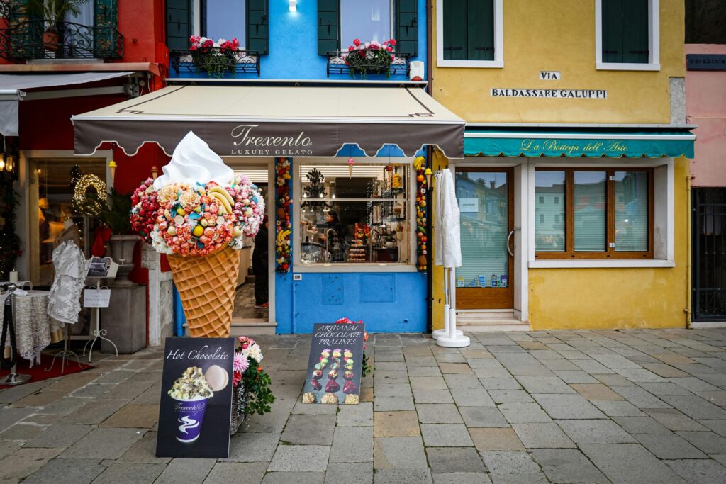 Vibrant gelato shop façade with colorful buildings on a picturesque street.