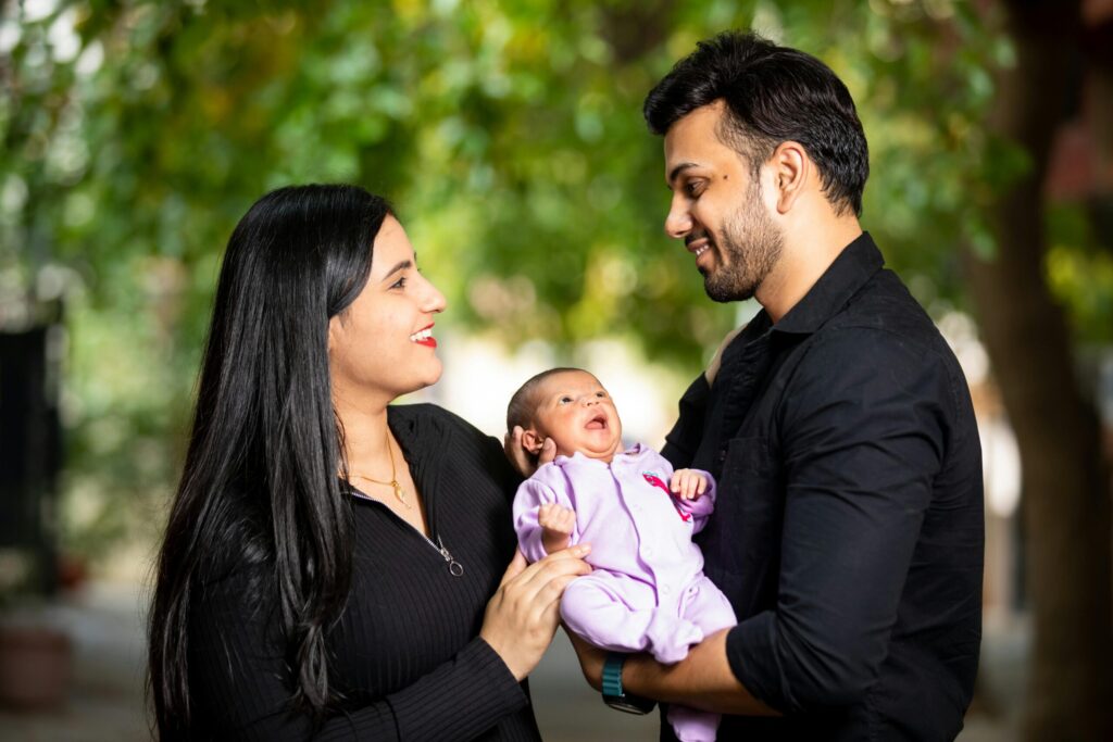 Happy family holding their newborn baby outdoors, filled with love and smiles.