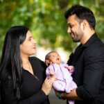 Happy family holding their newborn baby outdoors, filled with love and smiles.
