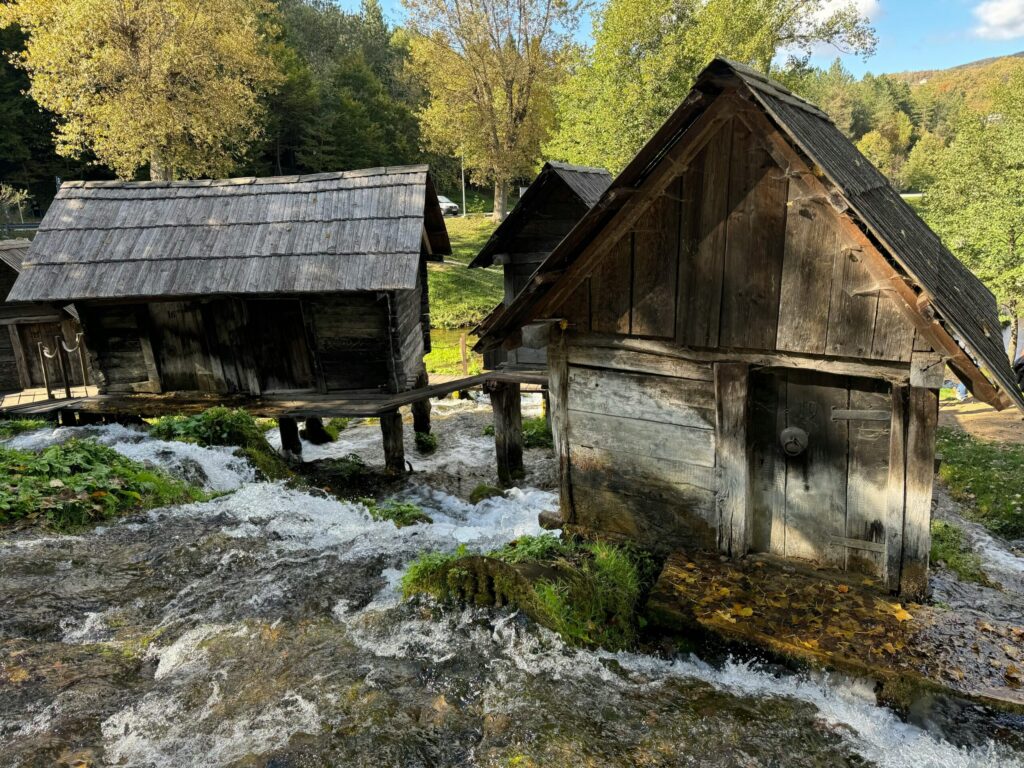 Wooden watermills in scenic forest setting with flowing stream. Beautiful natural and historical landscape.