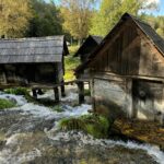 Wooden watermills in scenic forest setting with flowing stream. Beautiful natural and historical landscape.