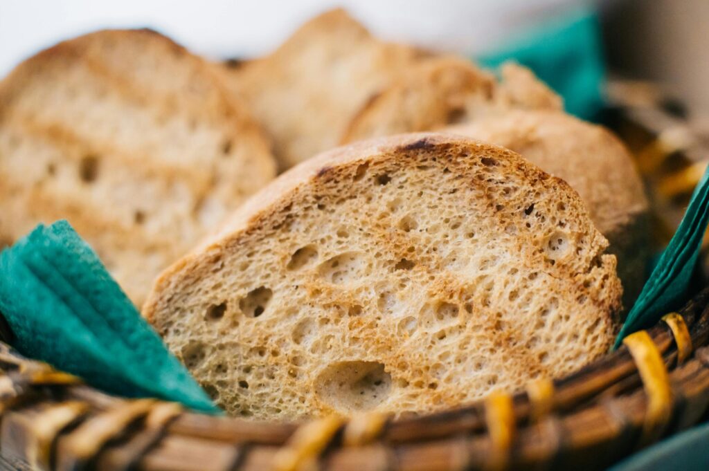 Close-up of rustic bread slices in a wicker basket, ideal for food blogs.