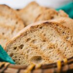 Close-up of rustic bread slices in a wicker basket, ideal for food blogs.
