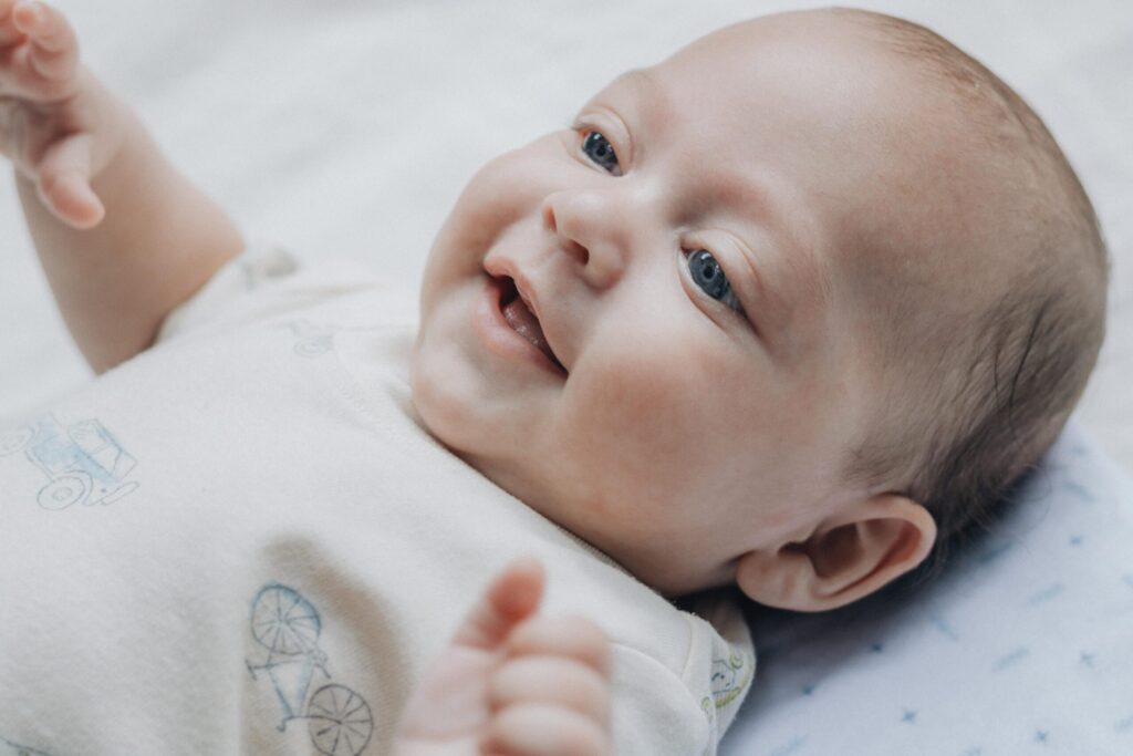 Adorable baby smiling and lying on a soft blanket, expressing happiness and warmth.