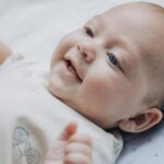 Adorable baby smiling and lying on a soft blanket, expressing happiness and warmth.