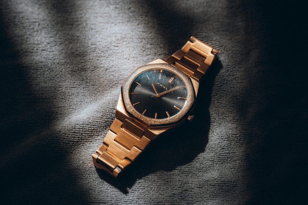 Close-up of a gold analog watch with a sleek design, artfully lit to highlight its elegance and style.