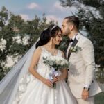 A romantic outdoor portrait of a bride and groom sharing a tender moment on their wedding day.