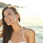 A woman enjoying a sunny day at the beach, smiling in her swimsuit.