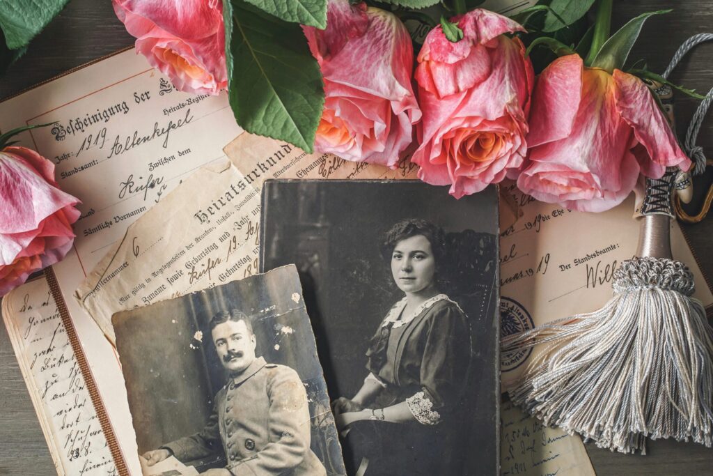 Antique family photographs with pink roses and historic documents.