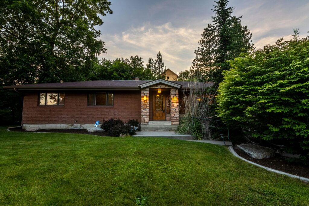 A cozy brick house surrounded by greenery, captured during twilight. Perfect for real estate promos.
