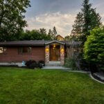 A cozy brick house surrounded by greenery, captured during twilight. Perfect for real estate promos.