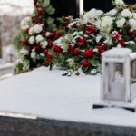 Grave adorned with roses and chrysanthemums in winter snow, evoking solemnity and remembrance.