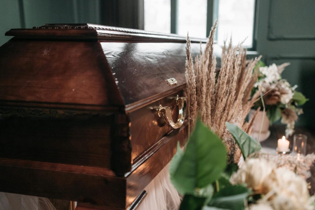 A beautiful funeral display featuring a wooden coffin with flowers and candles indoors.