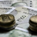 Detailed close-up of Indian rupee coins on top of banknotes, representing finance.
