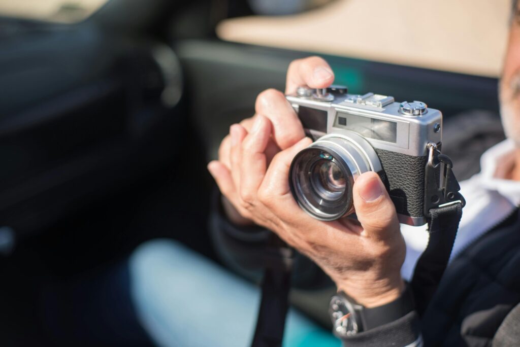 A person holding a vintage camera outdoors on a sunny day, capturing moments in Portugal.