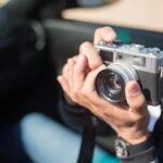 A person holding a vintage camera outdoors on a sunny day, capturing moments in Portugal.