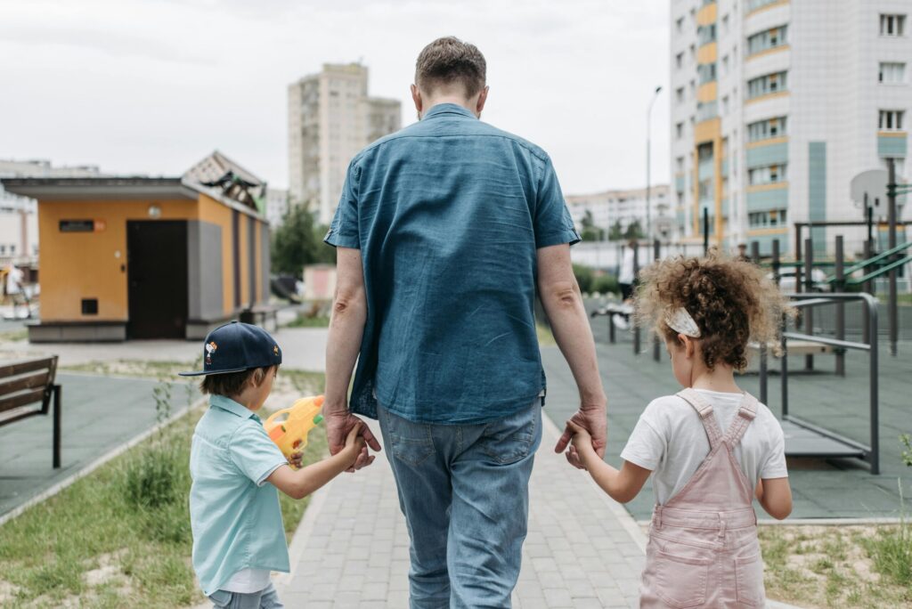 Father and children holding hands, enjoying a walk in a city park.