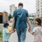 Father and children holding hands, enjoying a walk in a city park.
