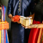 A vibrant scene of people in traditional Indian attire exchanging gifts during a festive celebration, like Diwali.