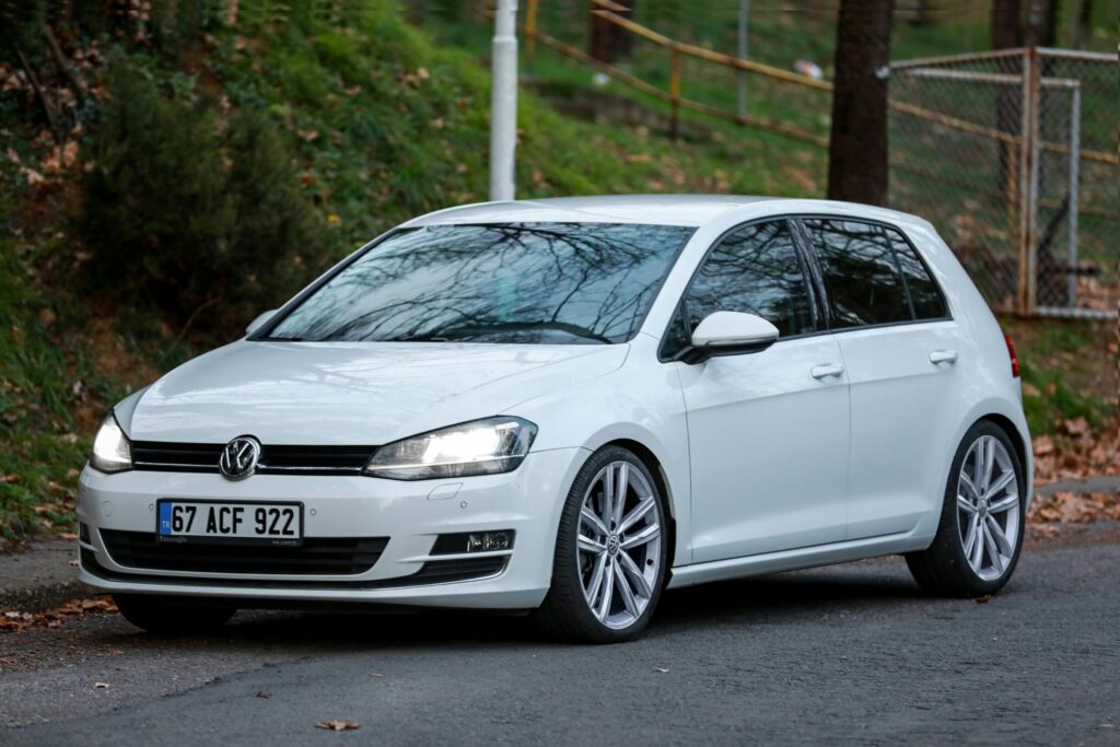A sleek white Volkswagen parked on an asphalt road in a lush green setting in Ereğli, Türkiye.