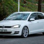 A sleek white Volkswagen parked on an asphalt road in a lush green setting in Ereğli, Türkiye.
