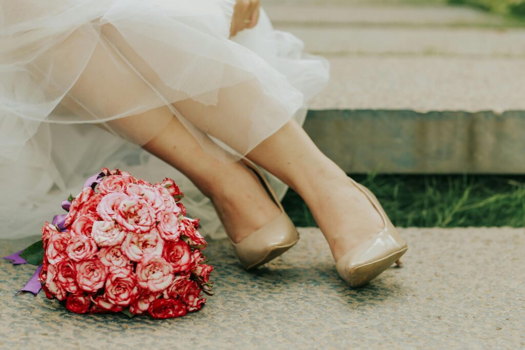 Close-up of a bridal bouquet with pink flowers and shoes on a sunny day.