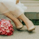 Close-up of a bridal bouquet with pink flowers and shoes on a sunny day.