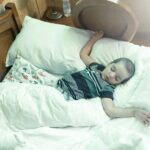 A young boy peacefully sleeping in a cozy bed surrounded by pillows and blankets.