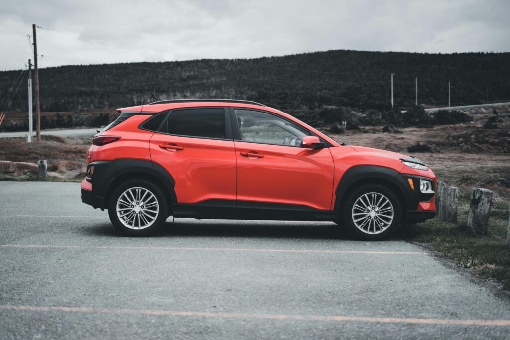 Red SUV parked outdoors on a cloudy day, showcasing sleek design and vibrant color.