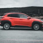 Red SUV parked outdoors on a cloudy day, showcasing sleek design and vibrant color.