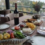 Elegantly set table with wine and gourmet dishes, offering a picturesque view of the landscape.