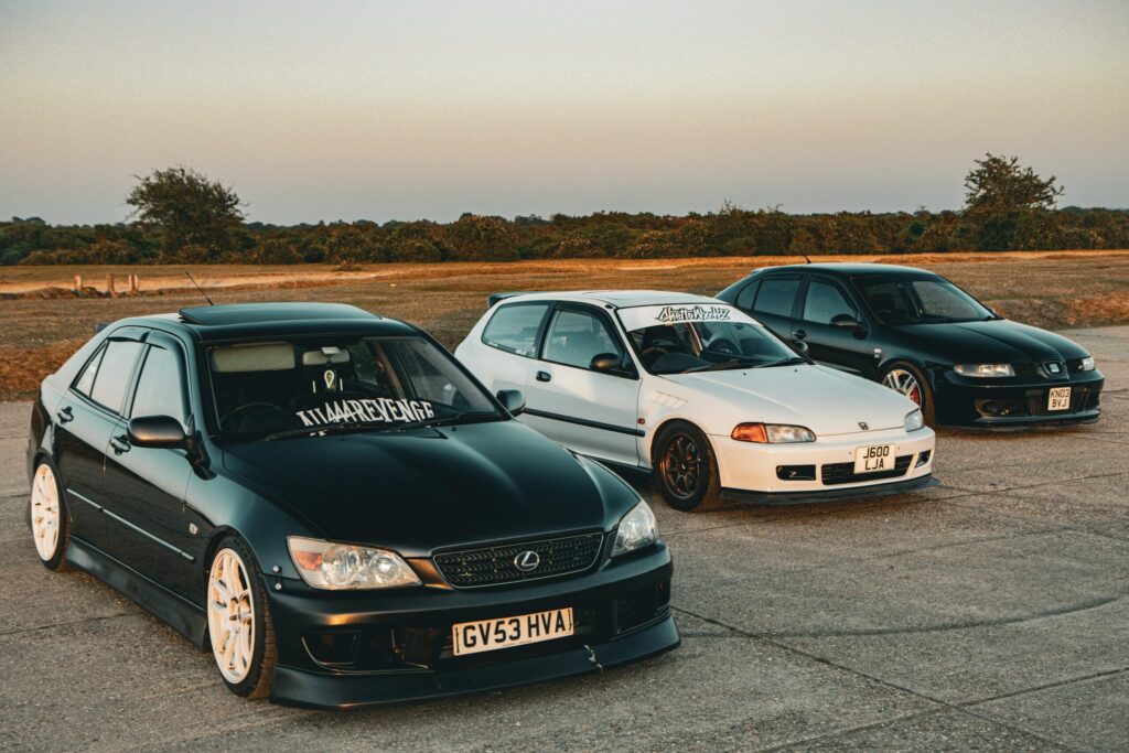 Three customized sports cars parked on open asphalt under a clear sky.