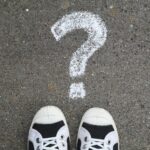 Sneakers on pavement with a chalk question mark, symbolizing curiosity or decisions.