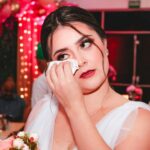 Bride wipes tears of joy while holding a bouquet during a heartfelt moment at her wedding.