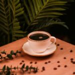 A warm coffee cup on a wooden table with plants and coffee beans, creating a cozy atmosphere.