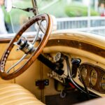 Close-up of a classic car interior showcasing a wooden steering wheel and vintage details.