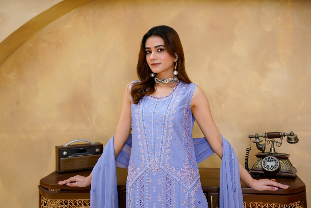 A woman in an elegant embroidered dress posing indoors in Lahore, Pakistan.