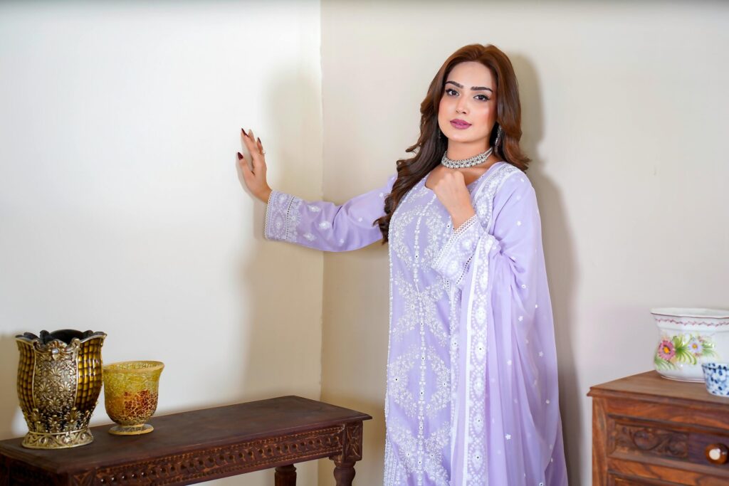Portrait of a woman in Lahore wearing a beautiful embroidered lavender dress with traditional decor.