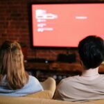 A couple watches TV together in a cozy brick-walled living room on a sofa.