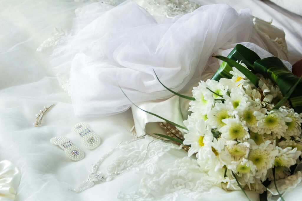 Elegant arrangement of bridal accessories with a white floral bouquet and veil, perfect for wedding themes.
